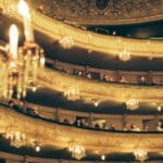 a group of people sitting on a stage with chandeliers