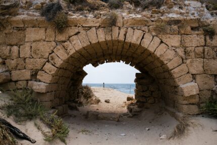 a stone tunnel on a sandy beach with the ocean in the background