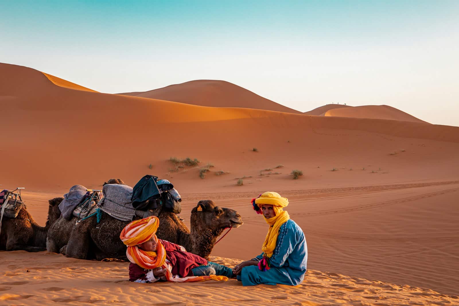 Ramal Tours – merzouga man in yellow robe sitting on brown sand during daytime