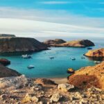 brown and green rock formation on blue sea under blue sky during daytime