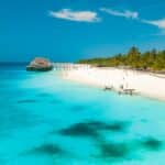 A white sand beach with palm trees and a wooden pier in Zanzibar, Tanzania